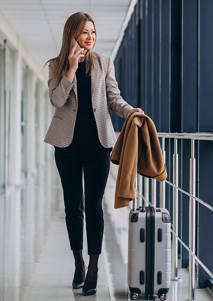 Business woman in terminal with travel bag talking on phone